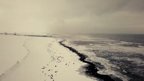 Cinematic-drone-moves-show-Black-sand-beach-in-Iceland-filmed-by-drone-in-snowy-conditions