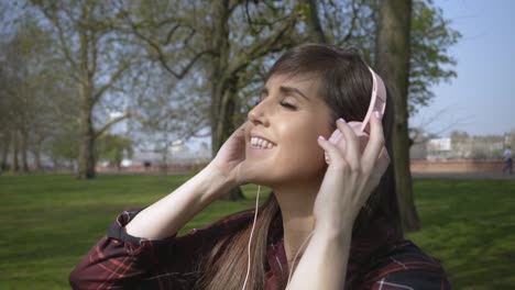 Kaukasische-Frau,-Die-Musik-über-Kopfhörer-In-Zeitlupe-In-Einem-Park-Hört