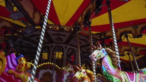 Slow-motion-view-of-Sicocks-fair-carousel-rotating-colourful,-Illuminated-horses-riding-on-poles