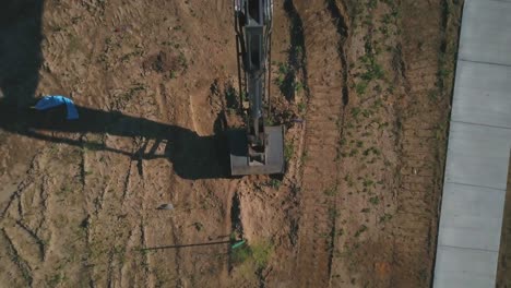 A-drone-pull-away-creating-a-bird’s-eye-view-of-a-backhoe-excavator-beginning-to-dig-a-hole-and-basement-for-the-foundation-of-a-new-house