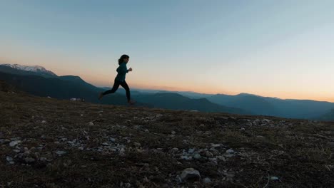 Young-girl-running-on-a-mountain-at-sunset-during-autumn