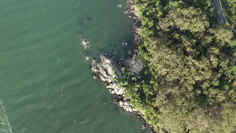 Top-aerial-panning-view-from-the-coast-of-Interpraias-road-at-Balneario-Camboriu,-Santa-Catarina,-Brazil-with-emerald-color-ocean