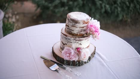Smooth-shot-of-a-beautiful-untouched-wedding-cake-sitting-on-a-table-during-a-wedding-reception