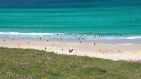 Meereswellen-Entlang-Der-Breiten-Sandküste-In-Sennen-Cove-In-Cornwall-Mit-Surfern-Und-Touristen,-Die-Am-Strand-Spazieren-Gehen