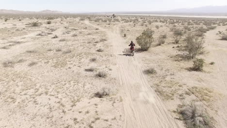 Aerial:-Ein-Dirt-Biker-Kommt-Schnell-Ins-Bild-Und-Fährt-Auf-Seinem-Honda-Crf-Motorrad-In-Die-Wüste-Davon