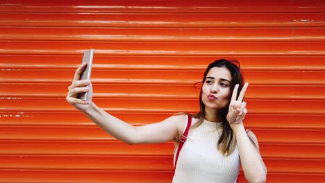Schönes-Junges-Mädchen-Macht-Selfie-Mit-Smartphone-Vor-Orangefarbenem,-Rotem-Hintergrund