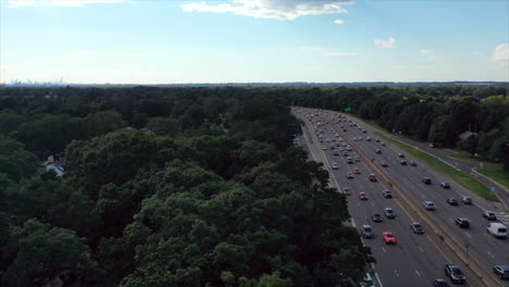 Hyperlapse-over-green-trees-with-a-highway-full-of-cars-zooming-by-on-the-right