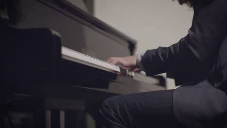 Male-pianist-performing-a-song-on-piano-with-low-light-and-shallow-depth-of-field-with-slider-motion