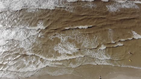 Top-down-view-of-the-waves-crashing-with-just-a-sliver-of-the-beach-visible