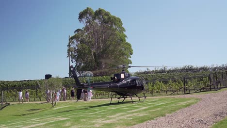 SLOWMO---Passengers-waiting-to-board-private-black-helicopter-at-winery-on-Waiheke-Island,-New-Zealand