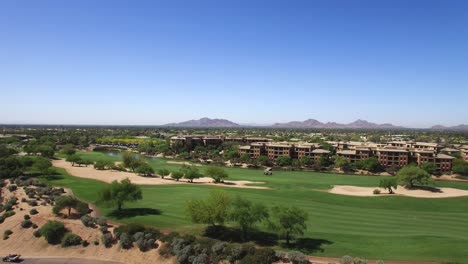 Aerial-pull-back-from-two-golf-carts-on-a-fairway-to-reveal-the-vast-resort-golf-course-complex,-Scottsdale,-Arizona-Concept:-desert-life,-resort,-exercise