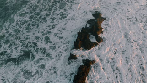 Drone-footage-taken-of-wild-crashing-waves-on-beach-and-rock-early-sunset-Asia