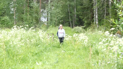 Best-friends,-nine-and-eight-years-old,-boys-strolling-in-walking-in-floral-summer-meadow,-STATIC-SLOW-MOTION
