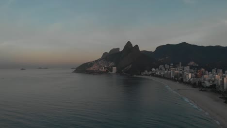 Luftaufnahme-Des-Berges-Der-Zwei-Brüder-Im-Hintergrund-Mit-Einem-Fast-Leeren-Frühmorgendlichen-Strand-Von-Ipanema-Im-Vordergrund-In-Rio-De-Janeiro-Bei-Sonnenaufgang