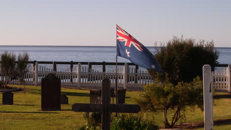 Ein-Grab-Aus-Dem-Weltkrieg-Mit-Der-Australischen-Flagge,-Die-Stolz-über-Seinem-Grabstein-Auf-Einem-Friedhof-Mit-Blick-Auf-Den-Ozean-Weht