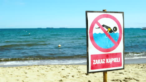 The-board-prohibits-swimming-on-the-seaside-beach,-no-swimming-today-on-sea,-information-board-for-tourists