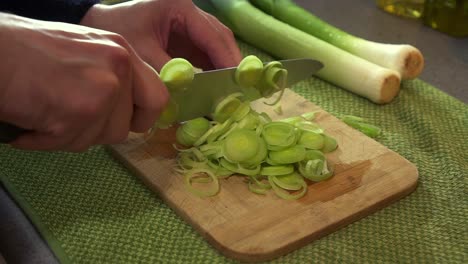 CU-Male-Chef-preparing-fresh-leeks,-chopping-them-with-a-sharp-knife-to-create-a-dish