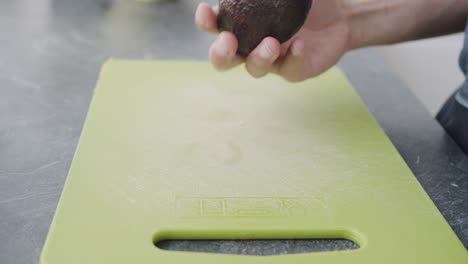 Static-shot-of-cutting-an-avocado-on-a-green-cutting-board