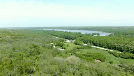 Aerial-shot-of-a-forest-with-a-lake-in-the-distance