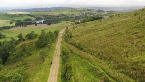 Aerial-footage-of-an-athletic-young-man-running-down-a-farm-path