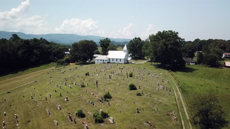 Beautiful-setting,-aerial-over-trees-flying-toward-church-chapel-with-mountain-backdrop