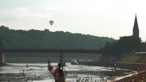Static-shot-of-hot-air-balloon,-church-tower-and-bridge-while-sun-is-shining