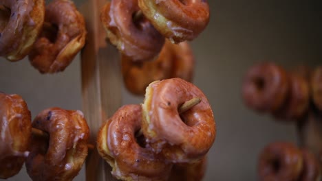 Slow-panning-shot-of-dozens-of-glazed-donuts-hanging-on-multiple-donut-racks