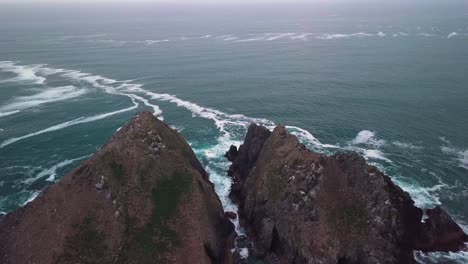 Flyover-drone-shot-of-a-rocky-island-in-the-middle-of-the-sea