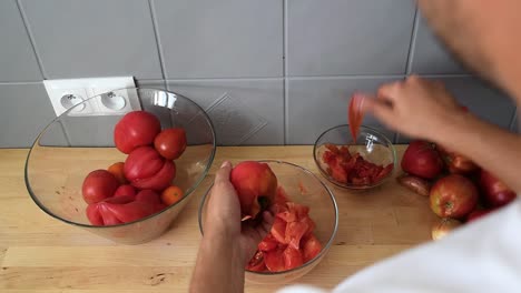 La-Mano-Del-Hombre-Cortando-Y-Pelando-El-Tomate,-Usando-Un-Cuchillo-Pequeño-Y-Afilado-En-La-Cocina-De-Una-Casa