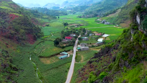Road-cuts-through-a-mountain-to-reveal-farm-land-nestled-in-a-misty-valley-in-northern-Vietnam