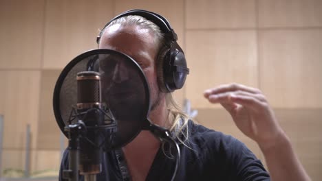 Front-view-of-singing-man,-pop-filter-and-microphone-close-up