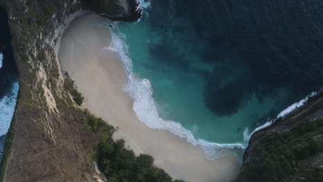 Beautiful-Tropical-Beach-Aerial-of-Holiday-Paradise---Bird's-Eye-view-of-Ocean-Waves-Crashing-on-Empty-Beach-Surrounded-by-Cliffs-from-Above