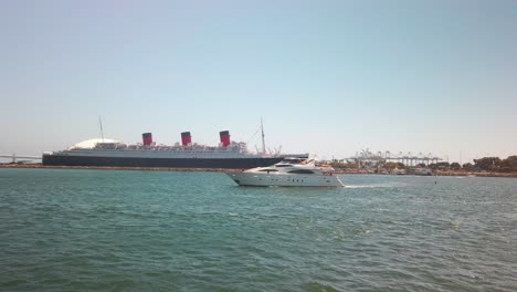 Huge-private-yacht-passes-through-port-entrance-with-giant-cruise-ship-and-Queen-Mary-in-the-background