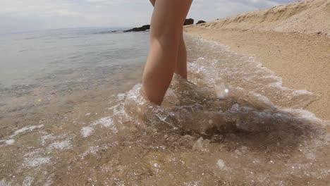 A-forward-dolly-camera-movement-of-a-girl-slowly-walking-on-a-sandy-beach