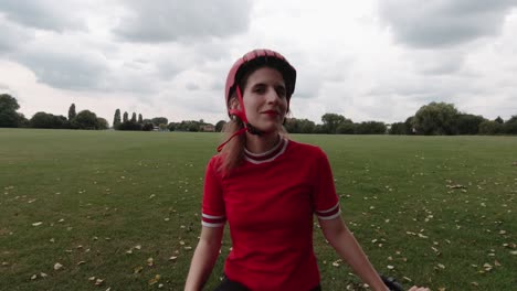 Caucasian-young-female-cyclist-puts-on-red-helmet