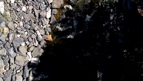 Ein-Sanfter-Flug-über-Einen-Fließenden-Fluss,-Umgeben-Von-Rauen-Felsen