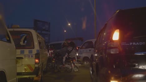 African-pedestrians-weaving-their-way-through-cars-and-motorbikes-in-a-busy-traffic-jam-in-East-Africa-and-night-time