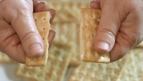 Close-up-of-Female-hands-breaking-a-cracker-in-half