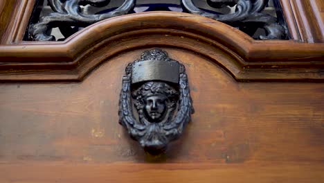 Old-wooden-door-with-metal-face-knocker