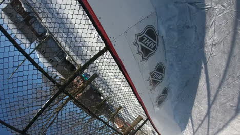 Einzigartiger-Blick-Auf-Einen-Puck,-Der-Während-Eines-Freiluftspiels-Auf-Einem-Eisfeld-In-Ein-Hockeynetz-Schießt