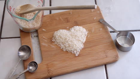 Weißes-Reiskorn-Animiert,-Die-Form-Eines-Herzens-Mit-Kochutensilien-In-Einer-Küchenschleife-Zu-Bilden