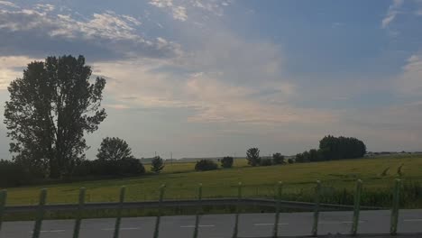 The-view-of-meadows,-clouds-and-roads-through-the-bus-window-while-driving