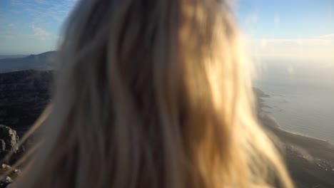 Slowmotion-over-the-Shoulder-on-top-of-Table-Mountain-in-Capetown-during-Sunset-with-a-Young-Blond-Woman