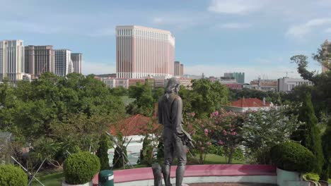Umkreisen-Sie-Die-Statue-Im-Carmel-Garden-Macau-Mit-Der-Skyline-Des-Casinos-Im-Hintergrund