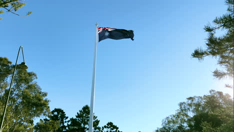 Bandera-Australiana-Ondeando-En-El-Viento-Con-El-Sol-Tratando-De-Alcanzar-Su-Punto-Máximo,-Toowoomba-Queensland