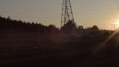 Tractors-in-the-sunset-in-rural-field-at-sunset-on-horizon