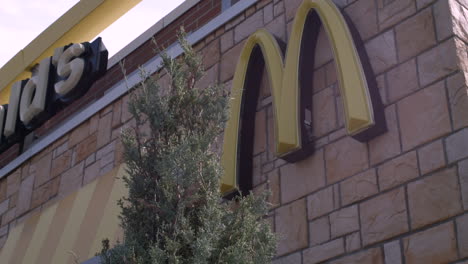 Stabilized-turning-shot-of-McDonald's-logo-and-brand-signs-on-the-exterior-of-a-restaurant-building