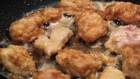 Close-up-on-chicken-nuggets-cooking-in-hot-oil-in-a-frying-pan,-Slow-motion