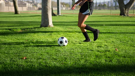 A-female-womens-soccer-player-running-and-dribbling-a-football-up-the-field-during-a-team-sports-practice-SLOW-MOTION