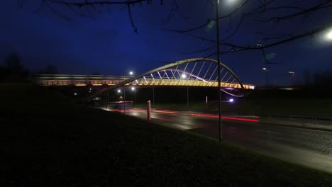 Steve-Prescott-bridge-Illuminated-timelapse-traffic-crossing,-St-Helens-Merseyside-speeding-traffic-under-colourful-lit-bridge